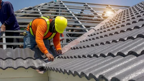 Construction worker repairing roof tiles