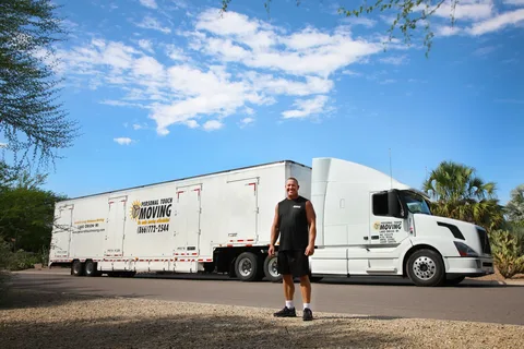 Man with moving truck on sunny street.